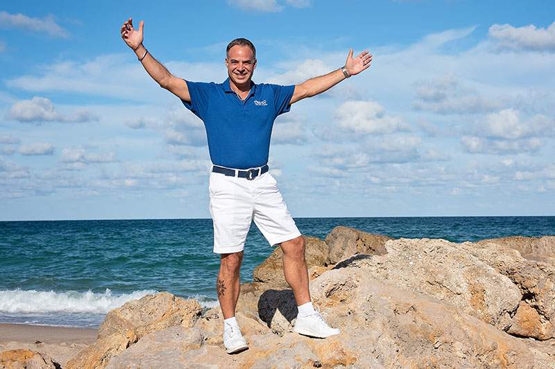 man on a rock on the beach with arms up