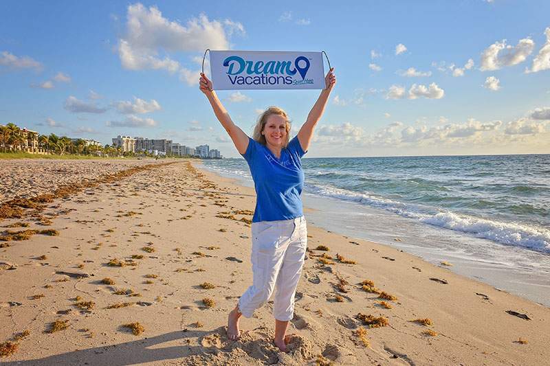 woman on beach holding Dream Vacations sign