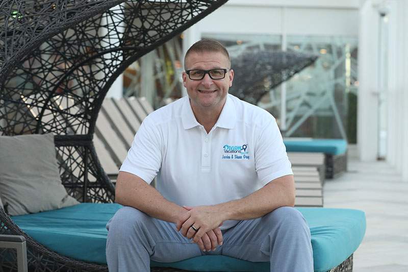 man with glasses sitting on a pool chair